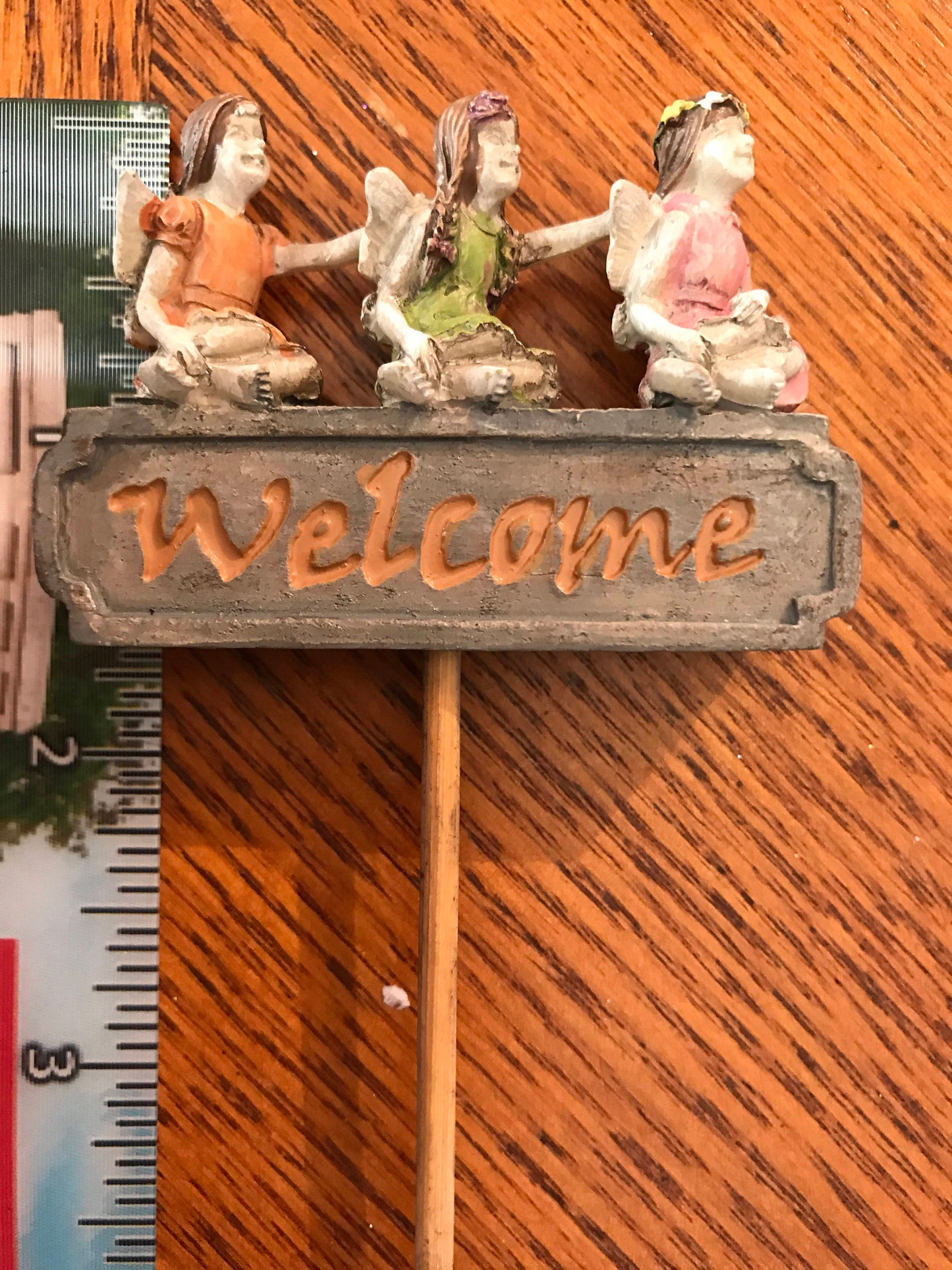 Three tiny fairies sitting upon a sign welcome you and your friends to your garden.