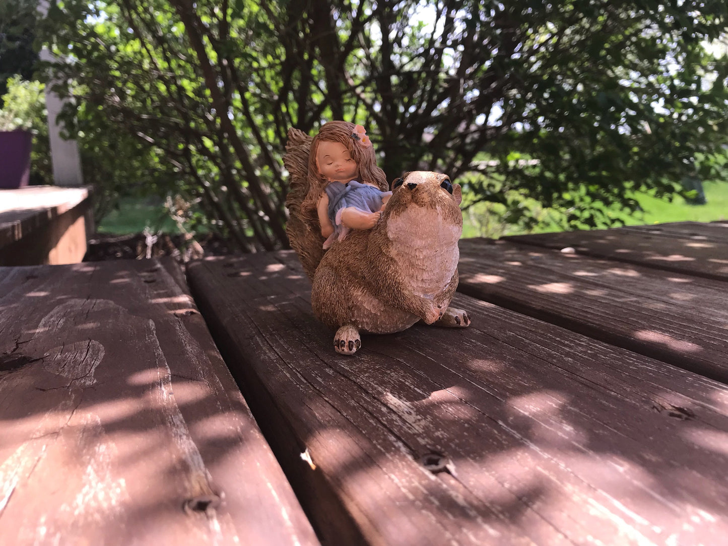 Little sleeping fairy on squirrel, outdoor garden