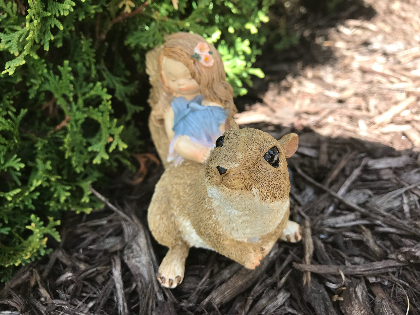 Little sleeping fairy on squirrel, outdoor garden