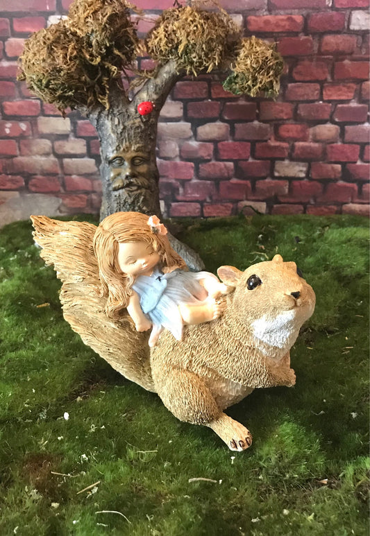 Little sleeping fairy on squirrel, outdoor garden