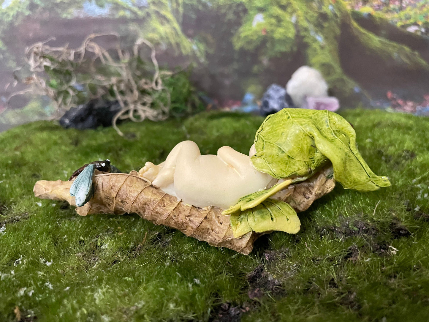 Baby Fairy laying on a leaf with a blue dragonfly looking on.