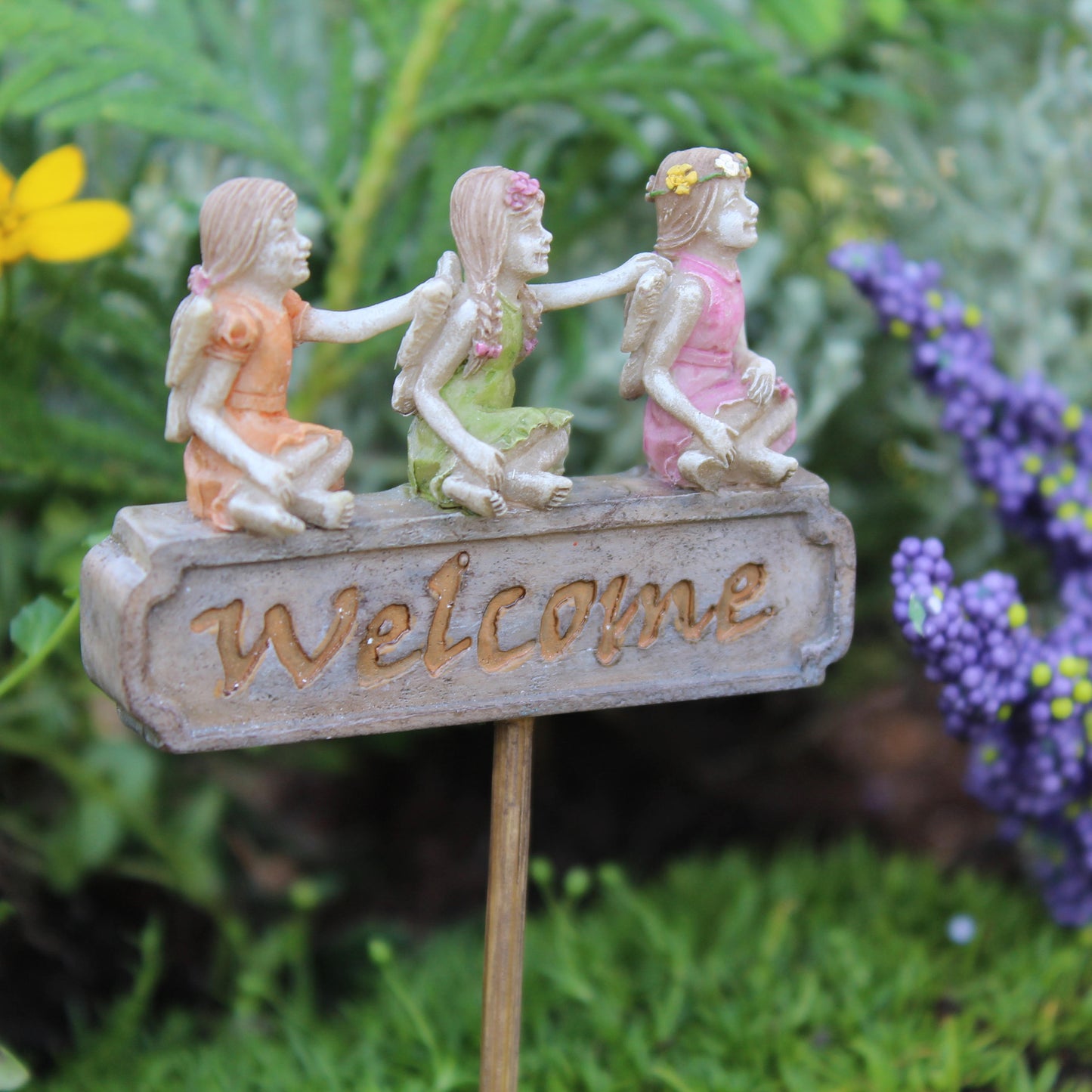 Three tiny fairies sitting upon a sign welcome you and your friends to your garden.